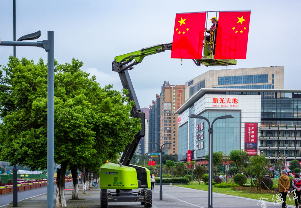 随着高空作业车的伸缩臂缓缓升起，一抹抹鲜艳的“中国红”飘扬在高空。图@向实